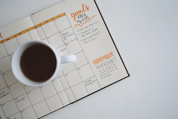 Organized family calendar on wall, woman reviewing it with coffee