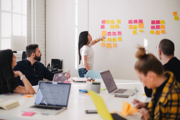 Woman presenting confidently at a whiteboard to a small attentive group